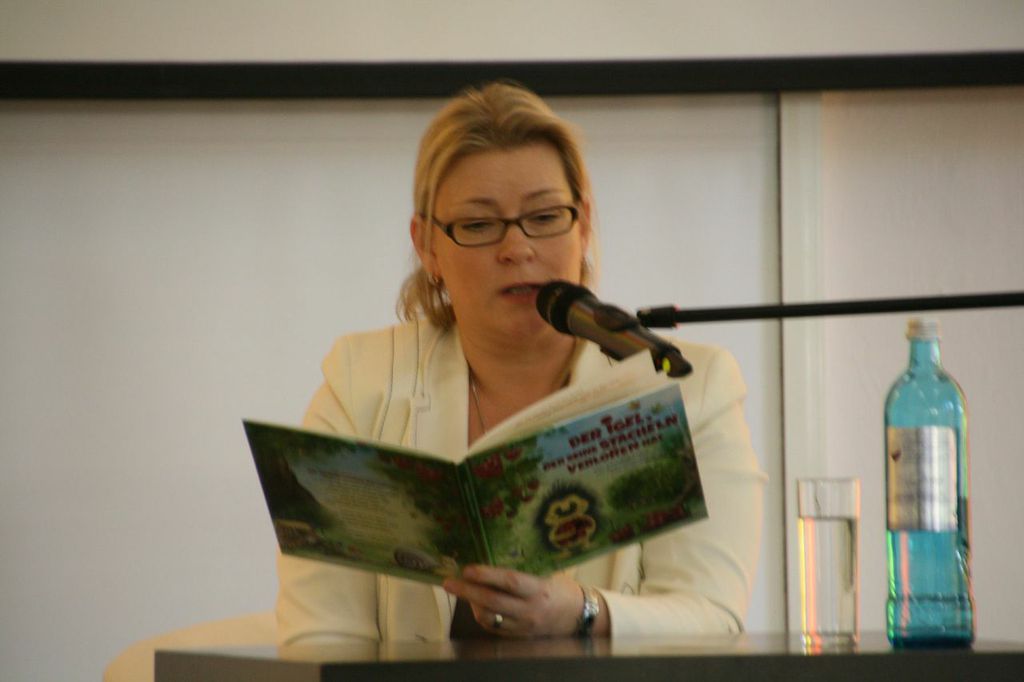 Autorin mit Buch in der Hand vor einem Mikrofon bei einer Lesung.