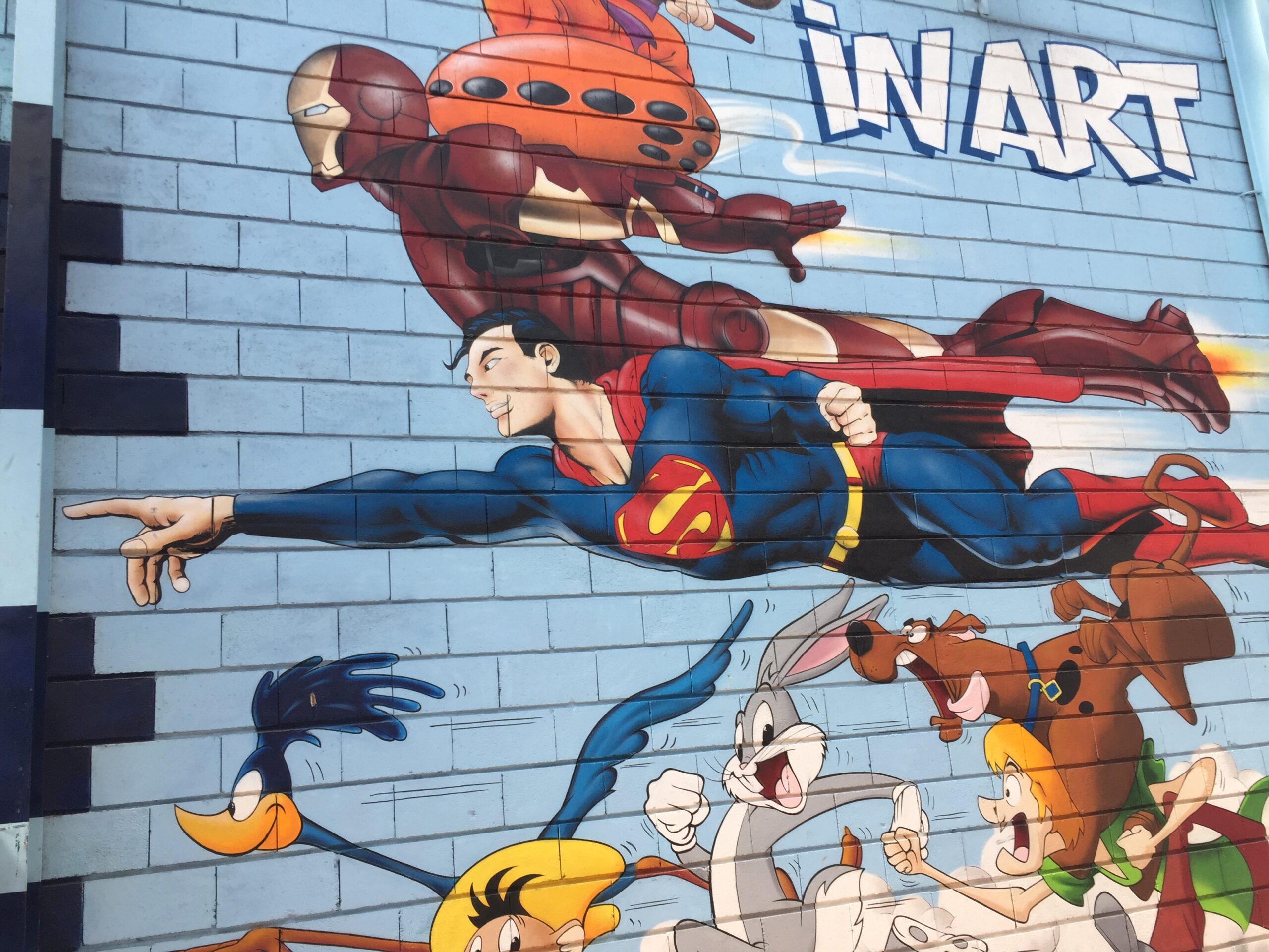 Mural auf hellblauem Hintergrund, sind Comic-Helden abgebildet, wie Superman, Bugs-Bunny und weitere