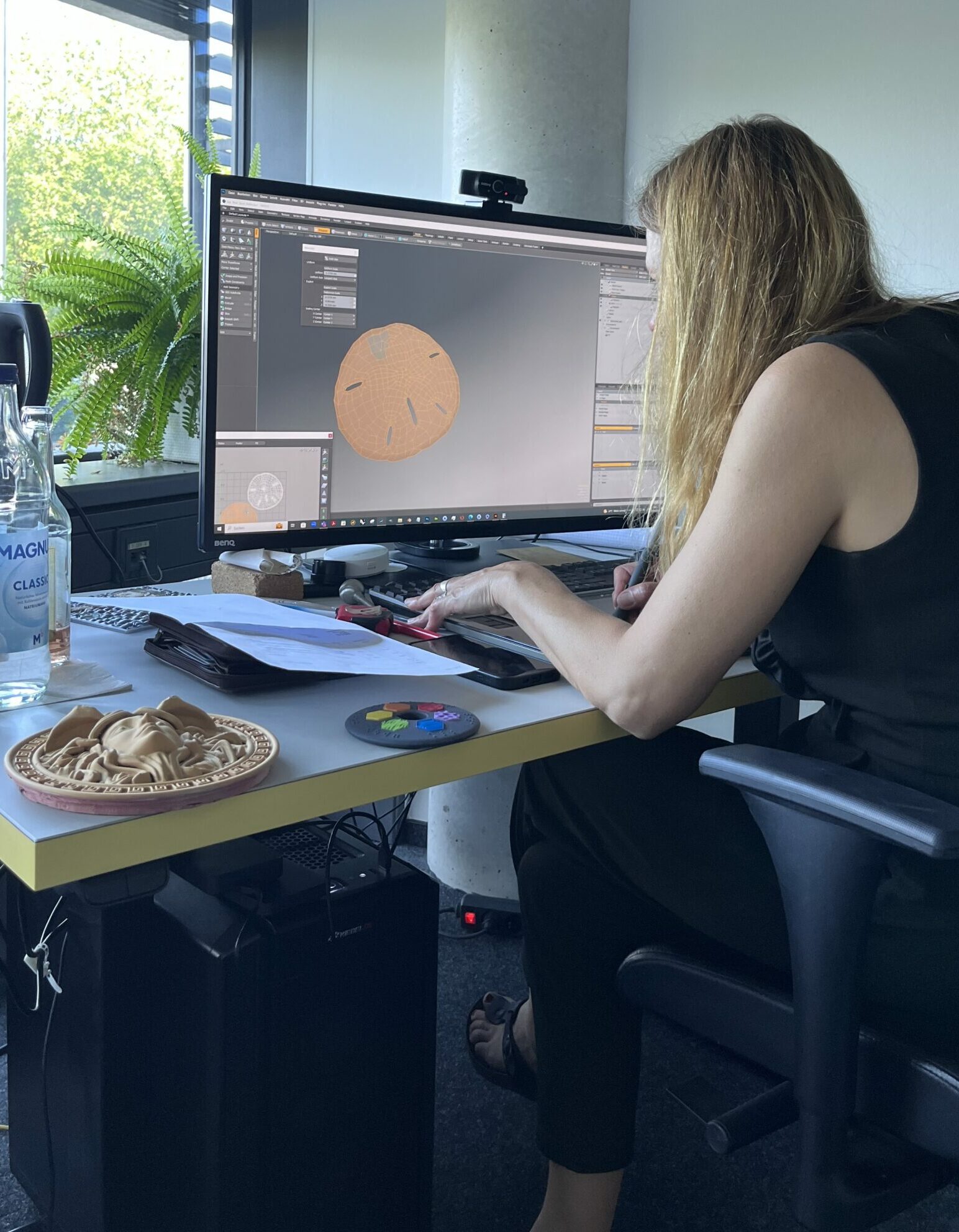 Blonde Frau sitz vorm PC und bearbeitet eine 3D-Druckdatei